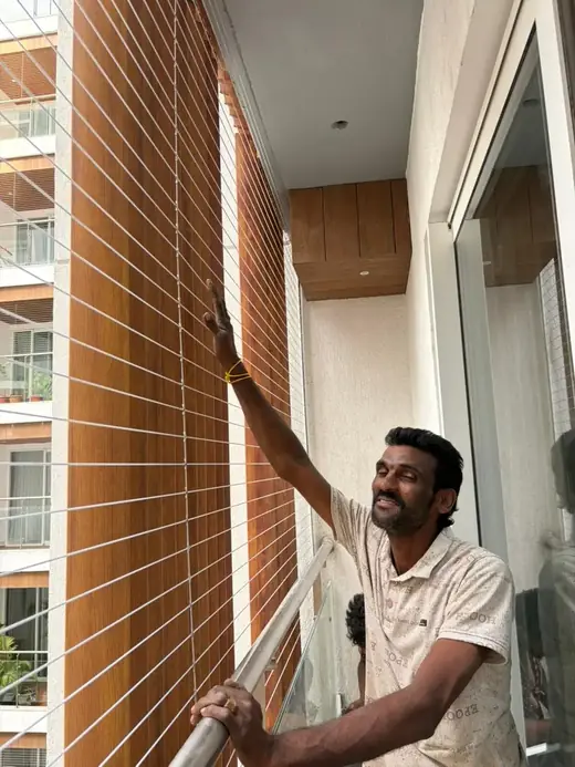 Installer inspecting a completed full-height balcony invisible grill fitting in Chennai