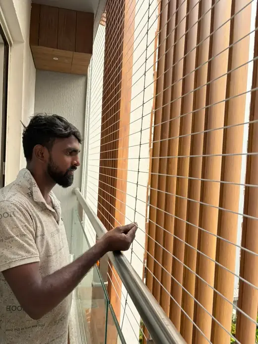 Close-up of rust-proof stainless steel invisible grill cables finished on a glass railing balcony in Chennai
